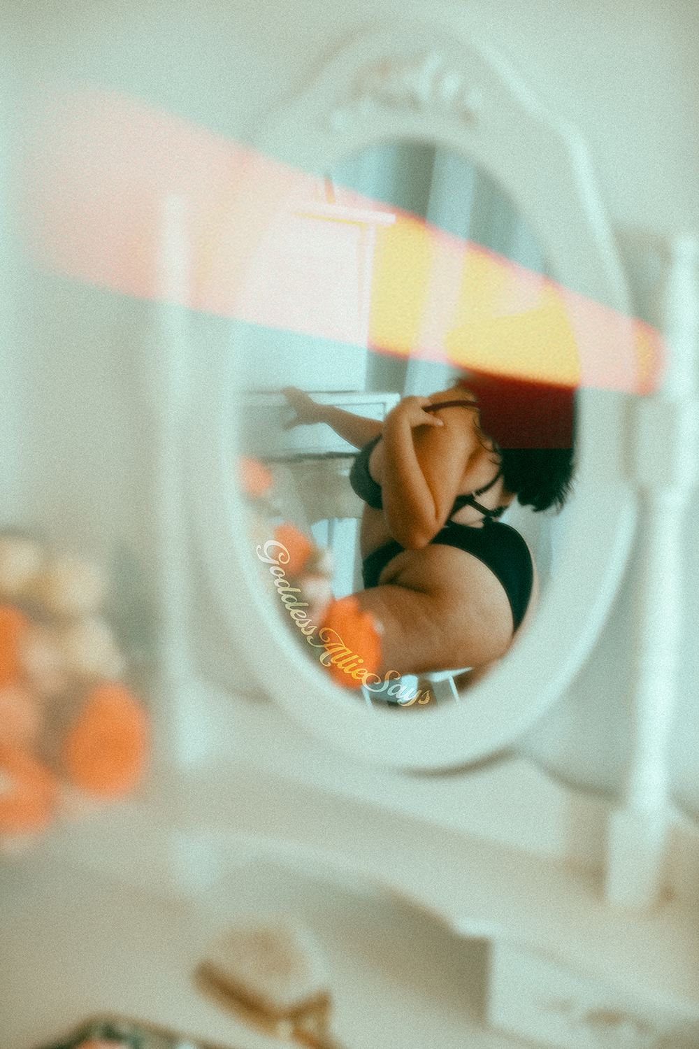 A mirror reflection of a plus size woman sitting at a piano wearing a black lingerie set, one hand pulling a strap off her shoulder.